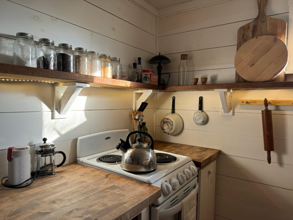 The glass jars, wooden cutting boards, and stainless steel appliances in this earthy kitchen make great less toxic alternatives.